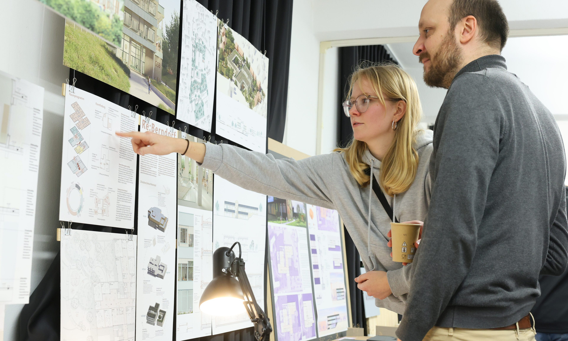 Ein Mann und eine Frau begutachten einen Beitrag der Ausstellung zur künftigen Nutzung des Wilke-Areals in Twistetal. Die Frau zeigt mit dem Finger auf ein Detail.