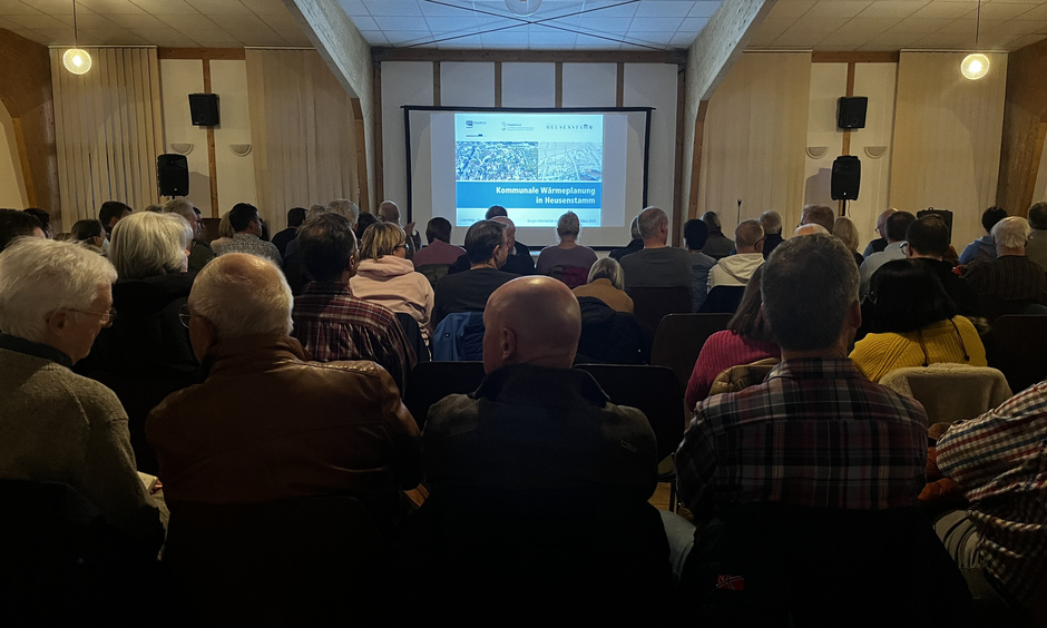 Die Bürger der Stadt Heusenstamm sitzen in einem Saal und schauen auf eine PowerPoint Präsentation.