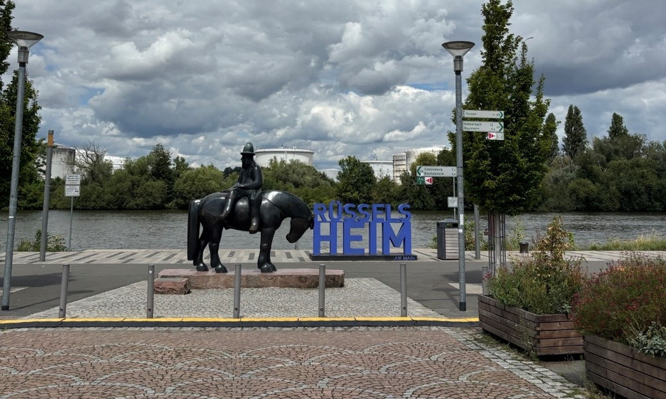 Zu sehend sind ein Platz mit einer Reiterstatue neben dem aufgestellten Schriftzug "Rüsselsheim".