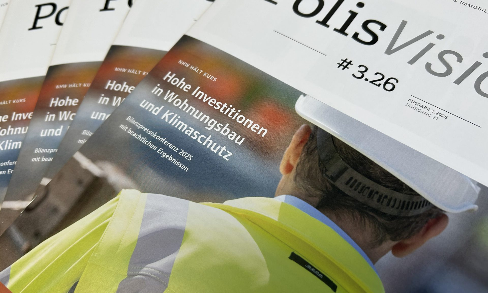 Mehrere aufgefächert fotografierte Ausgaben des NHW-Kundenmagazins PolisVision, Ausgabe 3/26 