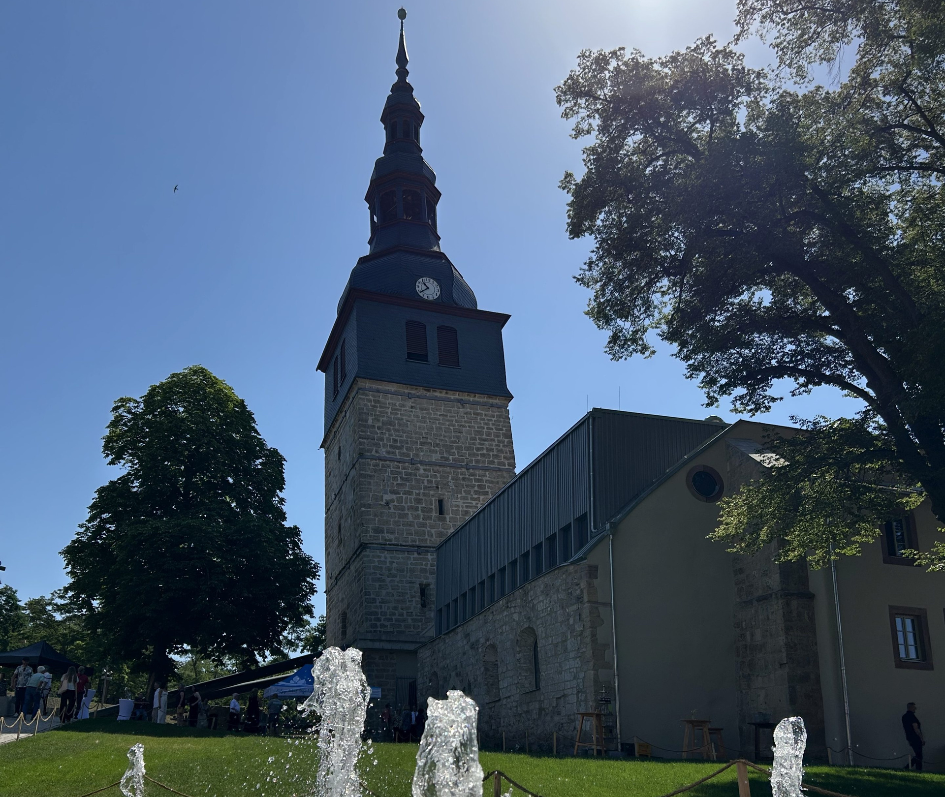 Der schiefe Kirchturm von Bad Frankenhausen mit einem Brunnen bzw. Fontänen im Vordergrund 