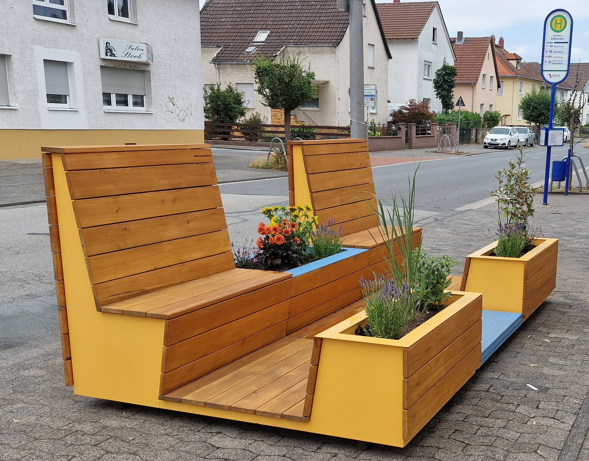 Bequem aussehende Sitzgelegenheiten aus Holz stehen auf einem Bürgersteig
