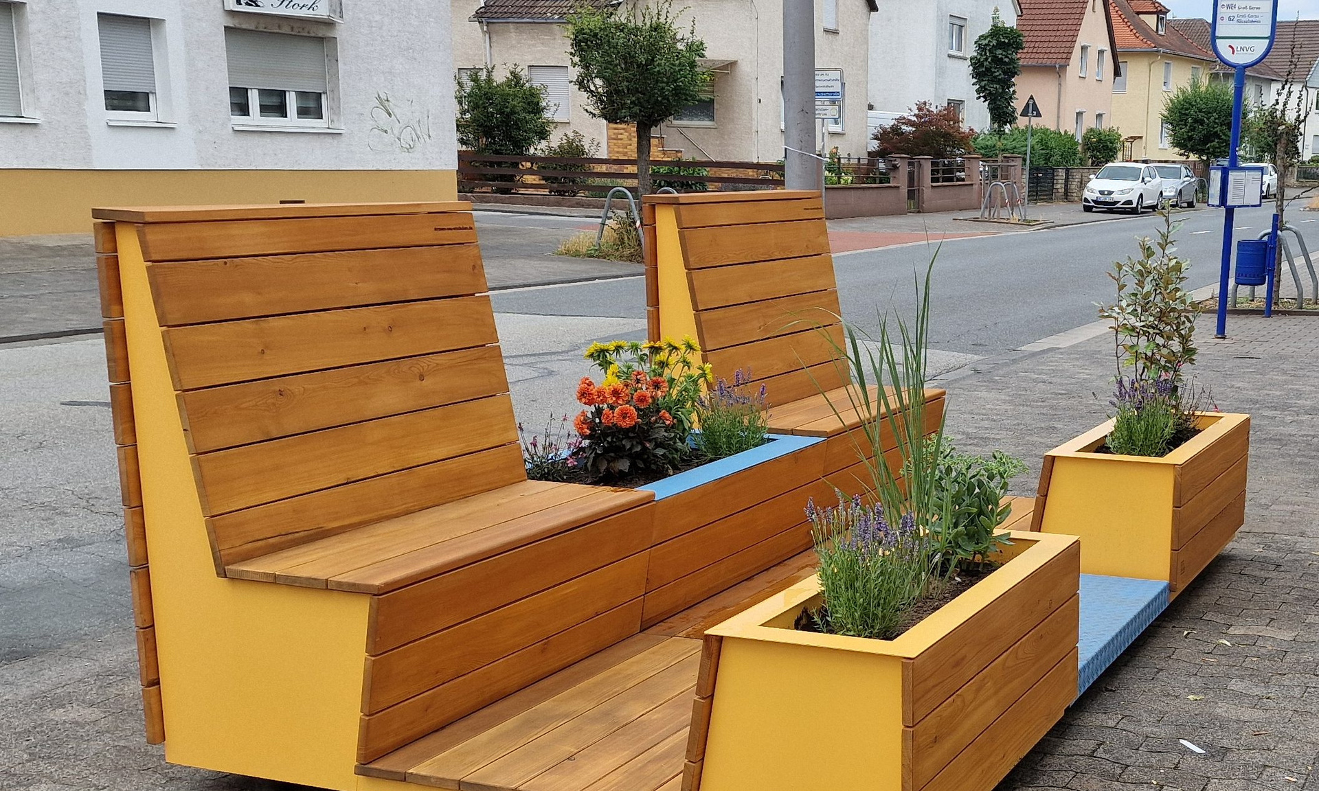 Bequem aussehende Sitzgelegenheiten aus Holz stehen auf einem Bürgersteig