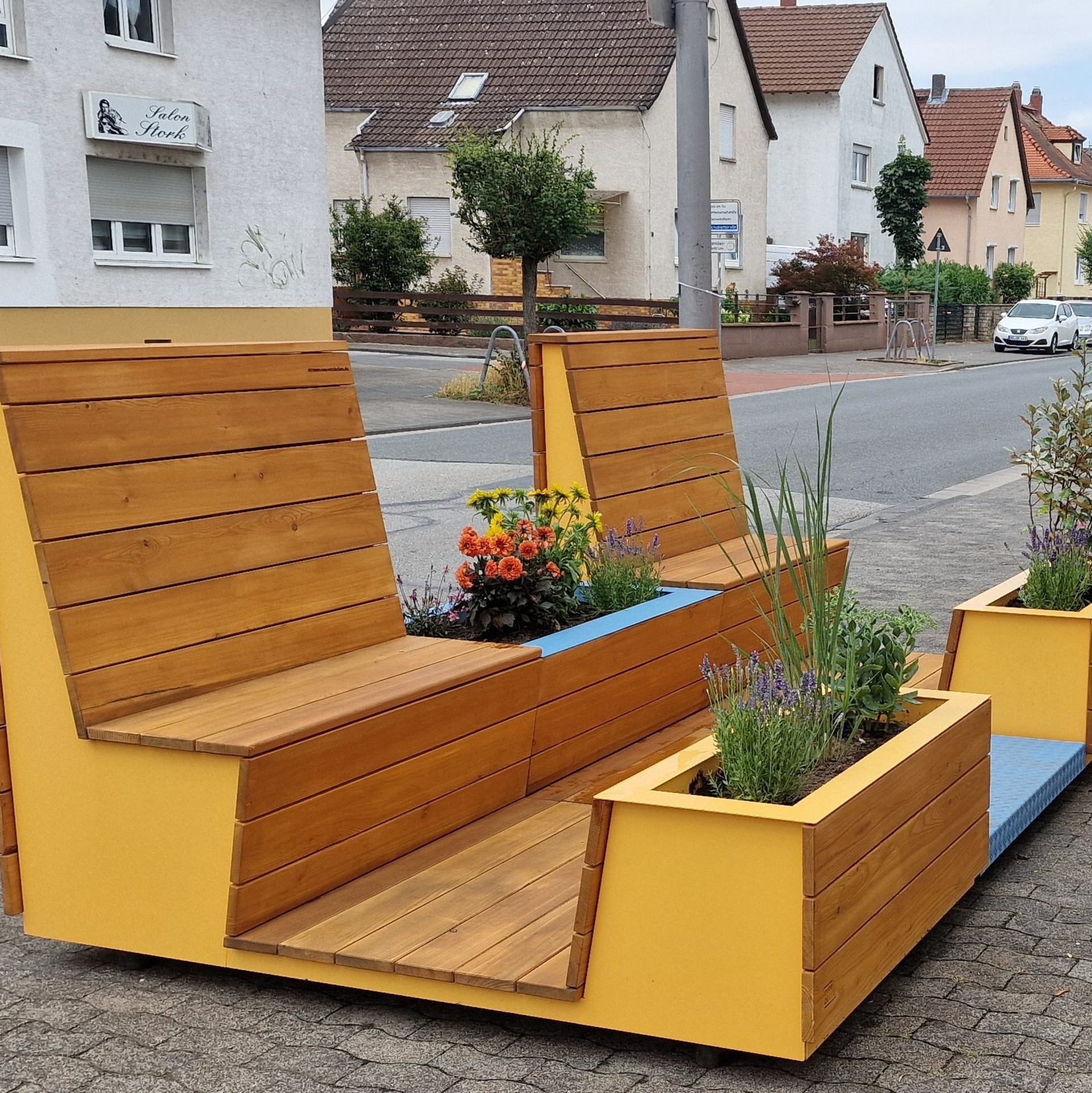 Bequem aussehende Sitzgelegenheiten aus Holz stehen auf einem Bürgersteig