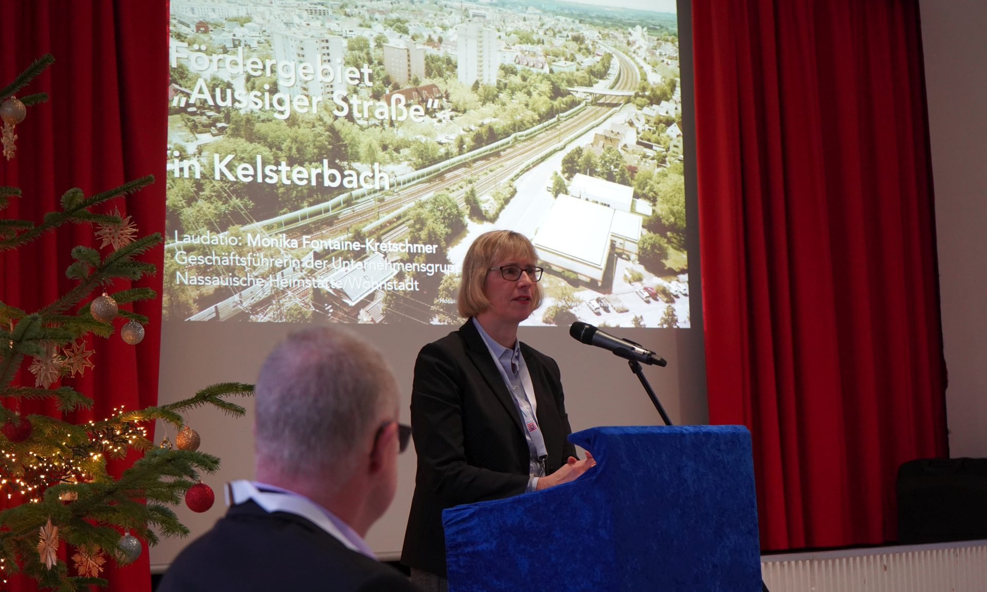 NHW-Geschäftsführerin Monika Fontaine-Kretschmer bei ihrer Laudatio für das Fördergebiet in Kelsterbach. Foto: Ministerium am Mikrofon