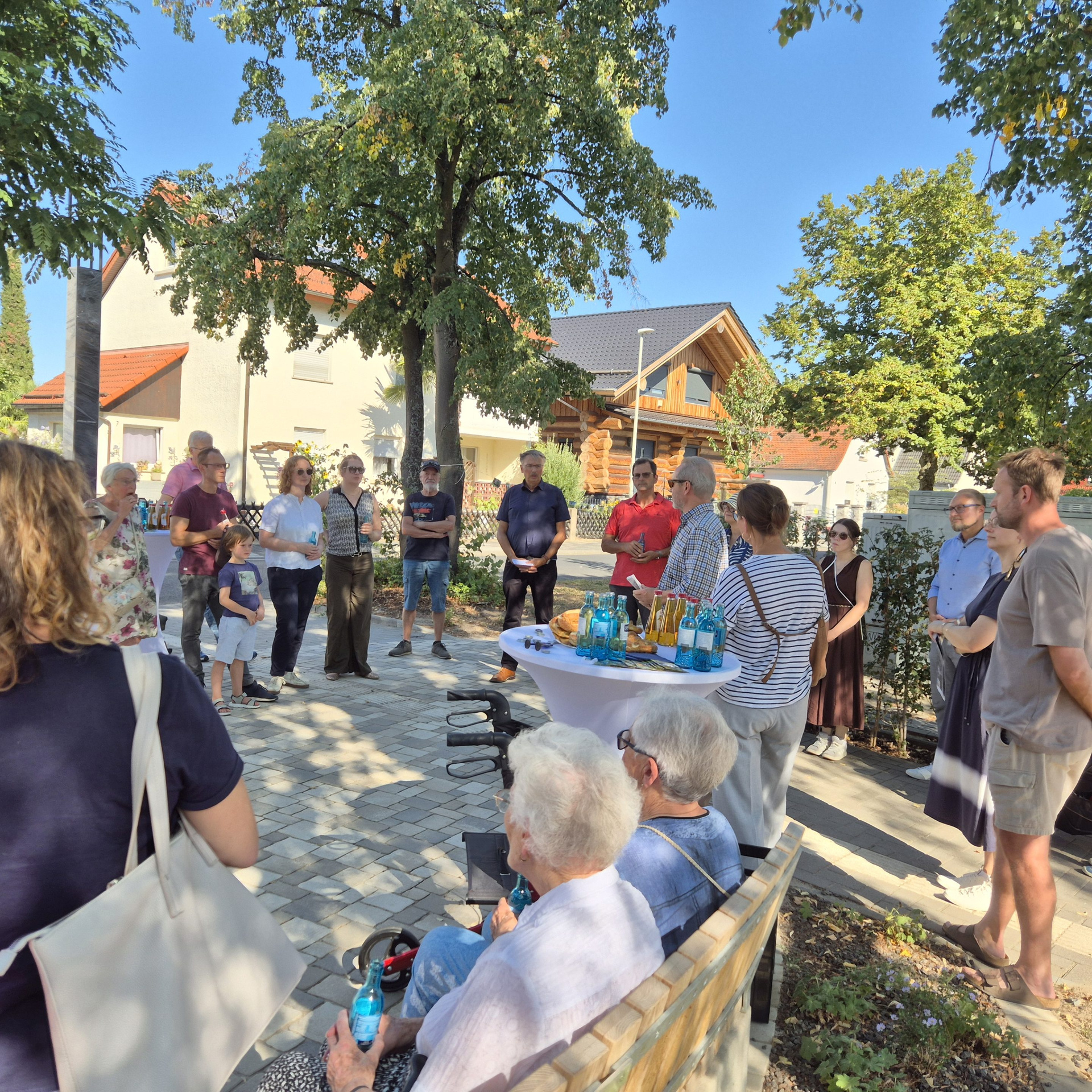 Feier mit rund 20 Menschen und einem neugestalteten Platz in Kelsterbach mit Bäumen, Bänken und Getränken