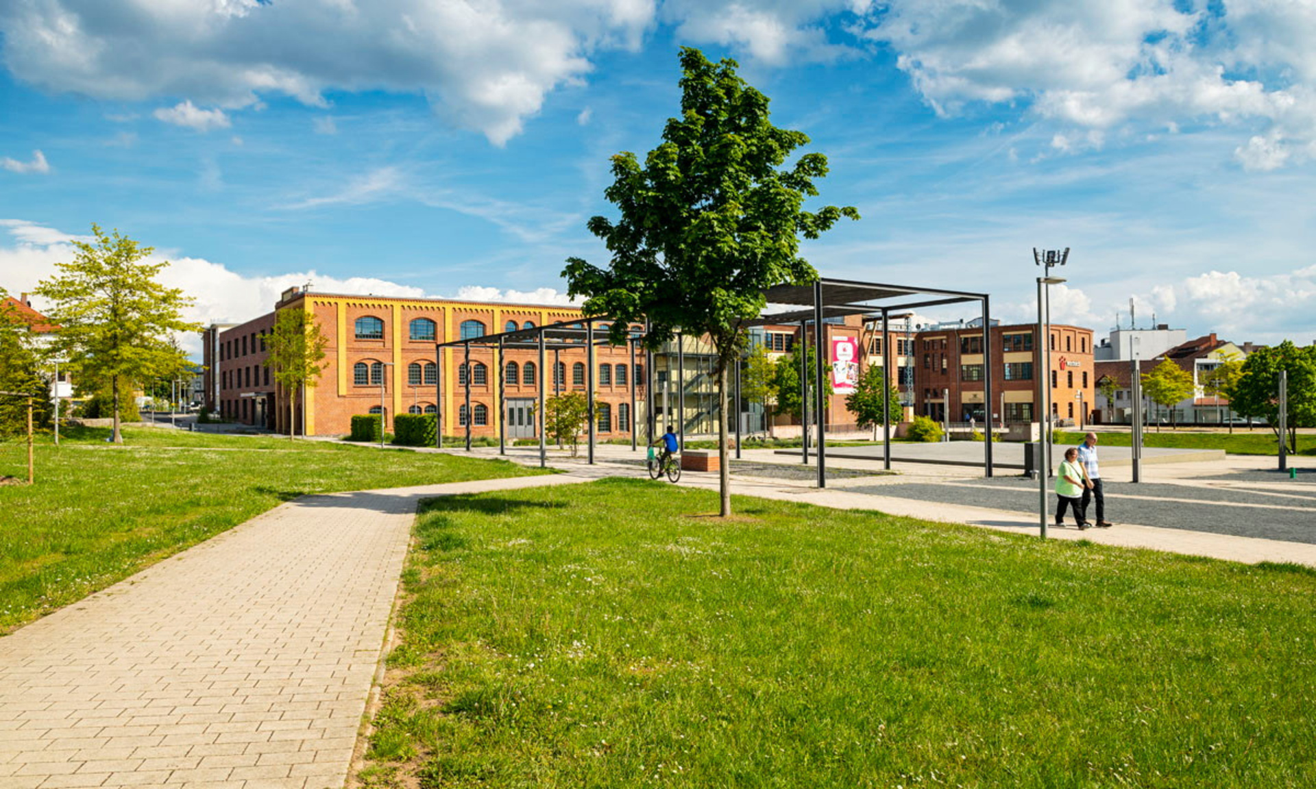 Grüne Wiese mit Fußweg, im Hintergrund altes Fabrikgebäude im Schilde-Park in Bad Hersfeld