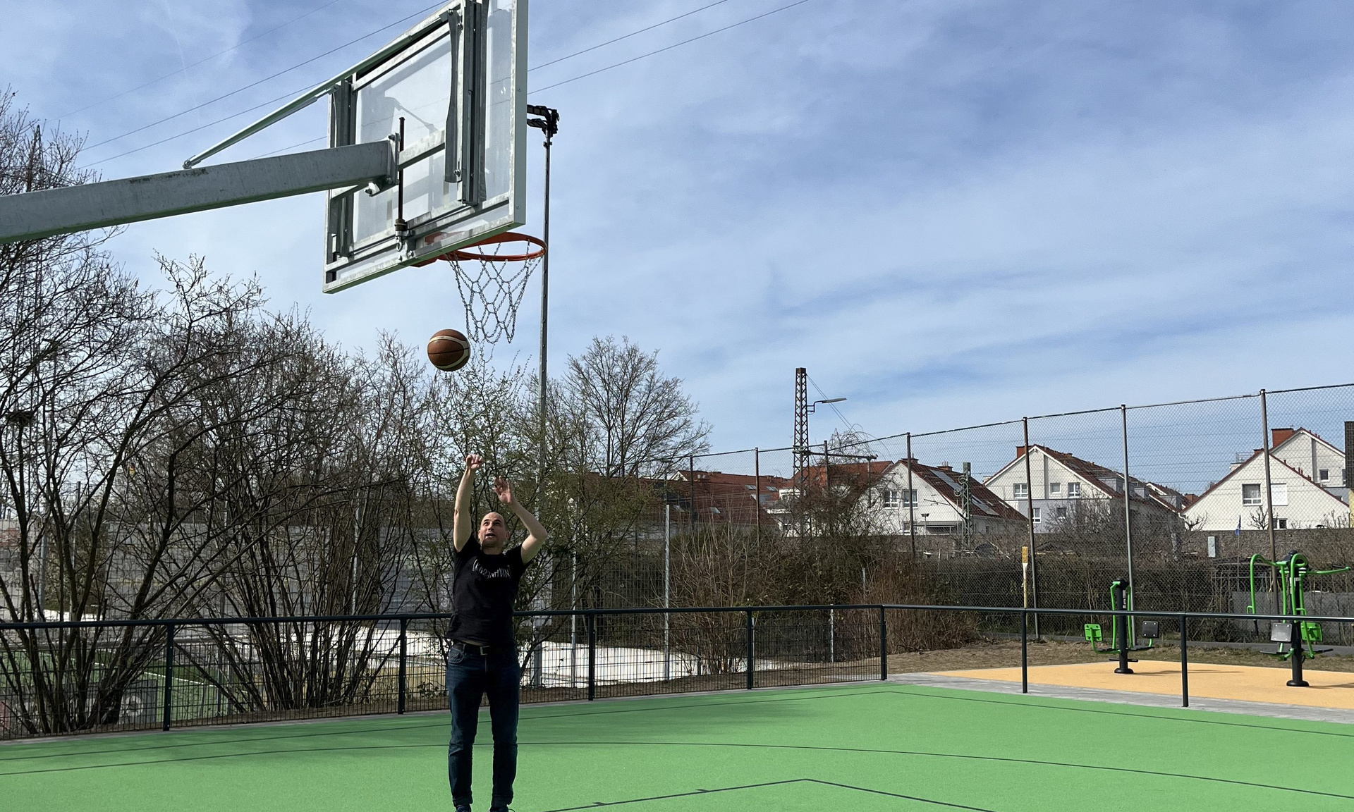 Ein Mann beim Wurf auf einen Basketballkorb auf einem Kunstrasencourt